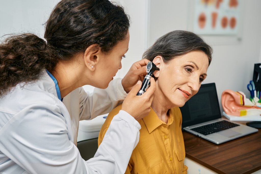 Medical professional checking woman's ear using otoscope or auriscope