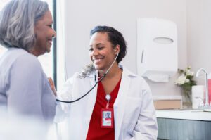 Smiling doctor listens to female patient's heart