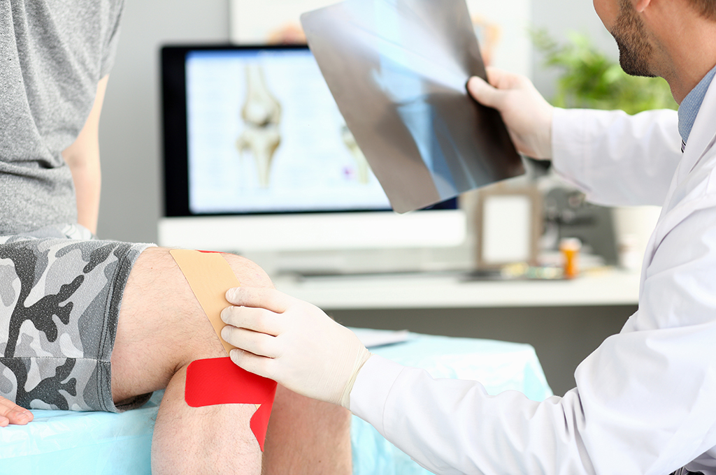 Doctor with patient holding xray shot of knee