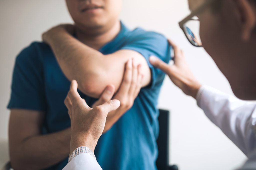 Physical therapist checks patient's elbows at the clinic