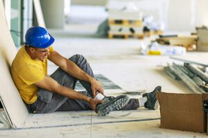 Male grabs ankle in pain at a construction site