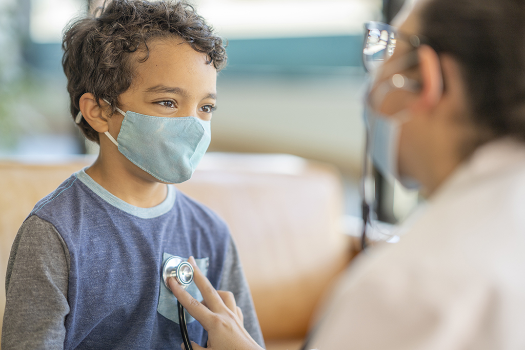 Hispanic doctor listening to a young boy patient's heart