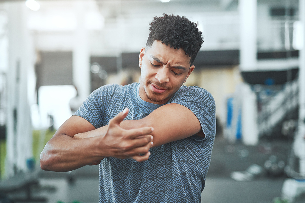 Male touching elbow in pain at gym