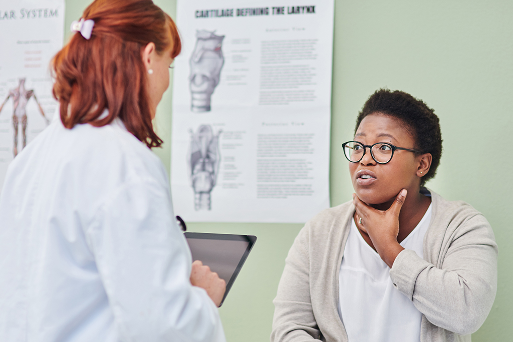 Doctor examining a woman’s throat during a consultation