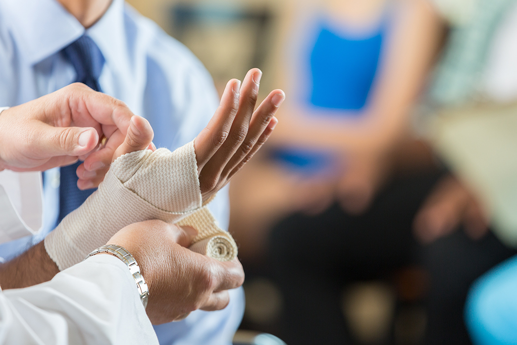 Patient having wrist bandaged by nurse