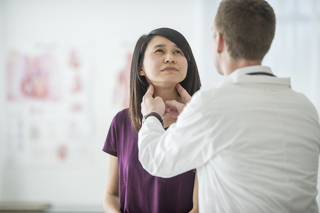 Doctor performing a thyroid cancer checkup on female patient