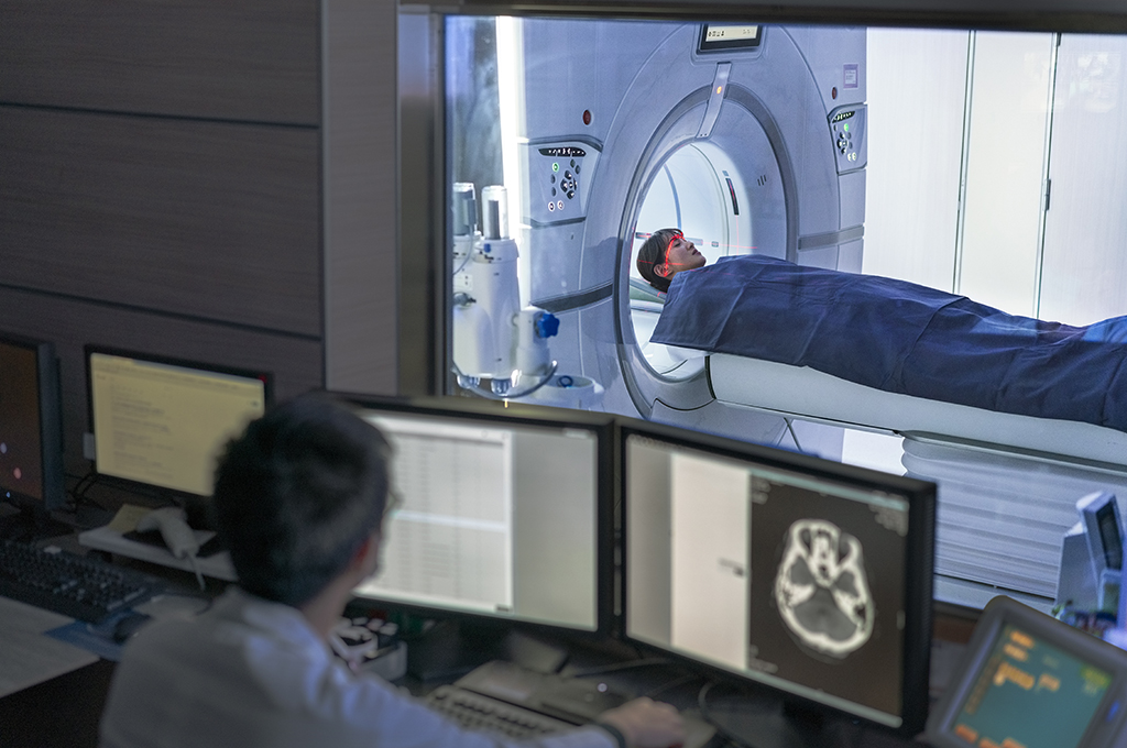 Doctor examining scan while patient in MRI scanner