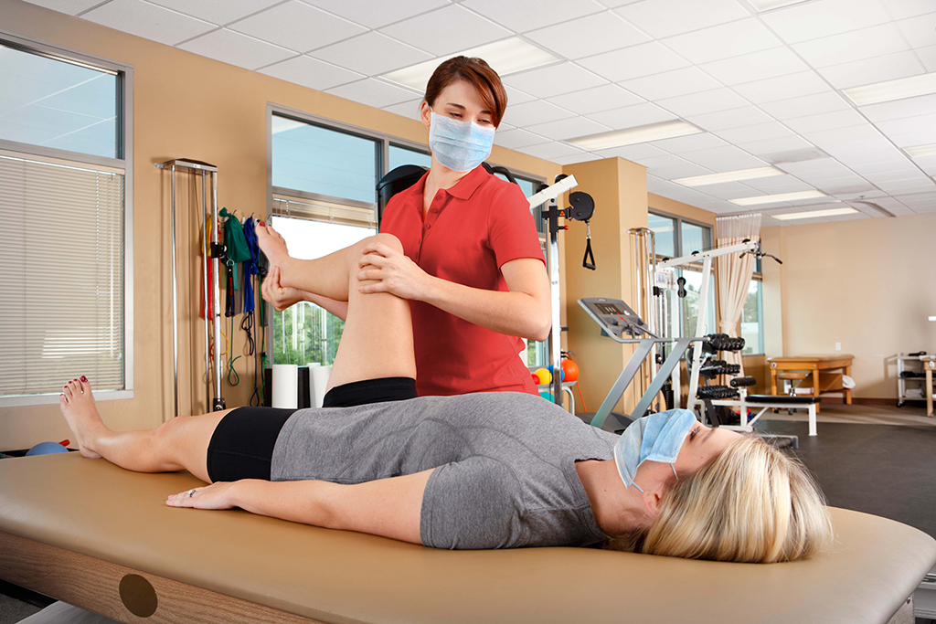 Female physical therapist helps female patient with her knee
