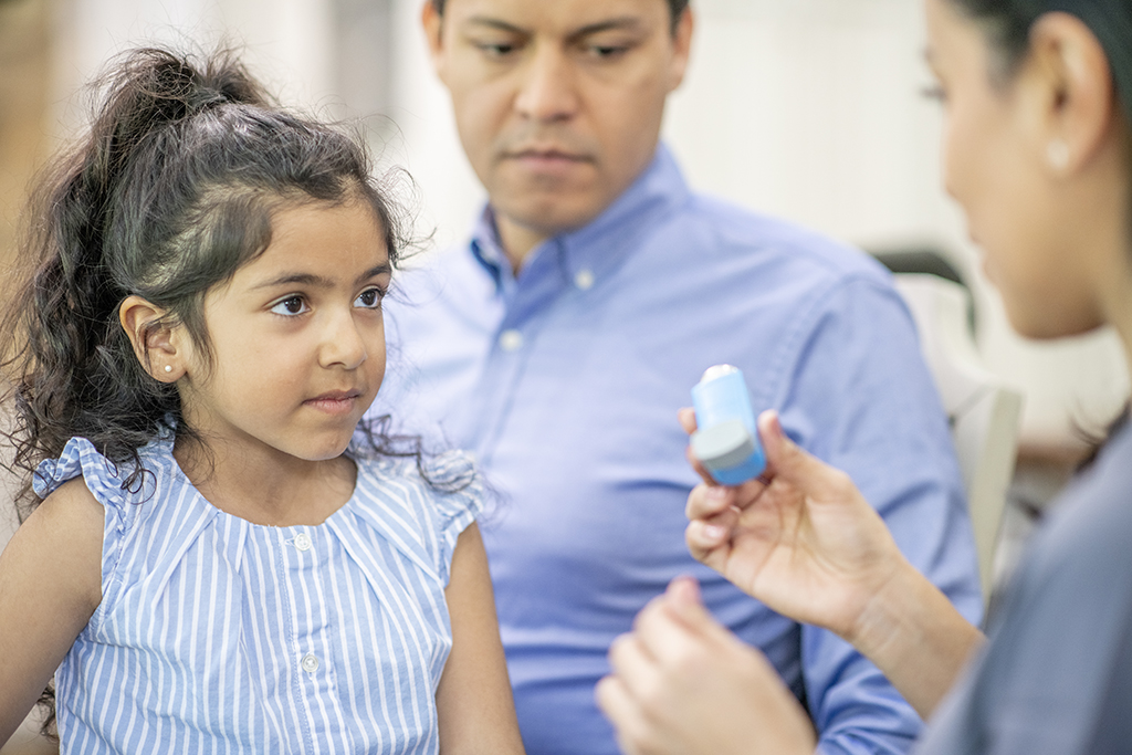 Young girl learning how to use an asthma inhaler