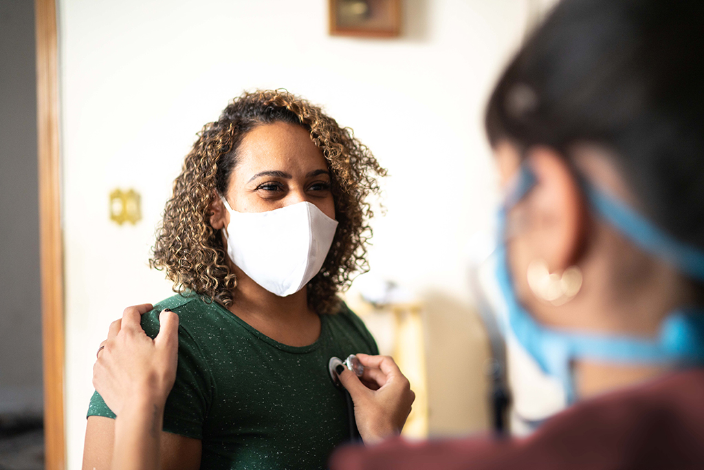 Female medical professional listens to female patient's heart