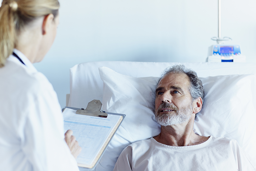 Doctor writing notes while talking to male patient