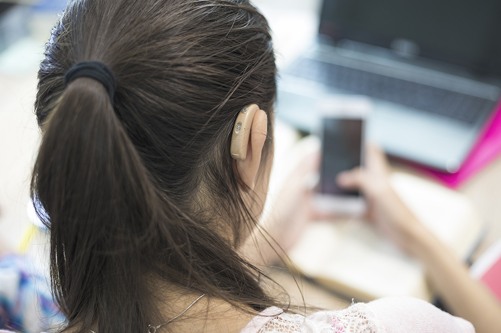 Girl with hearing aid on her phone