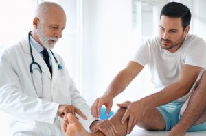 Young man having his ankle examined by medical professional