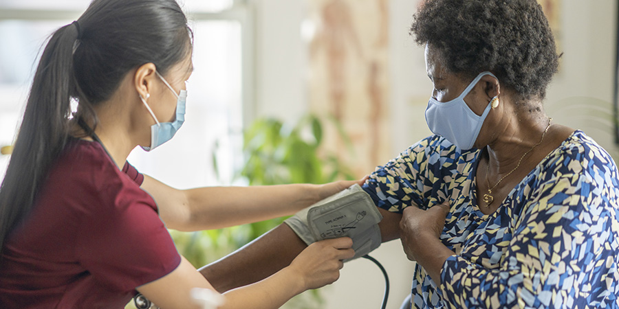 Female medical professional checking senior patient's blood pressure
