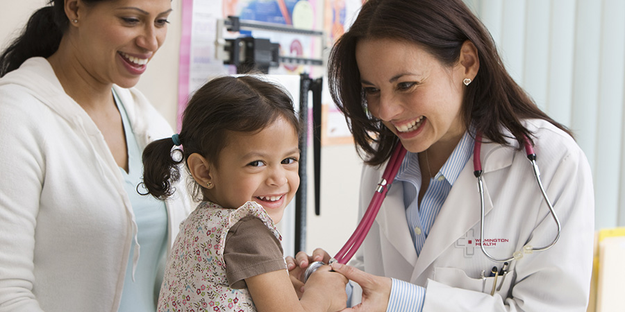 Toddler girl laughing while doctor examines