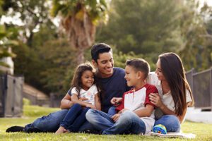 Hispanic family sitting together in the park, looking at each other