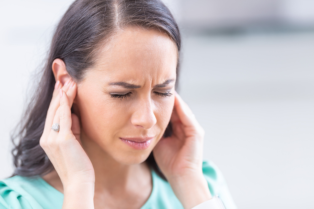 Young woman has headache, migraine, stress, or tinnitus
