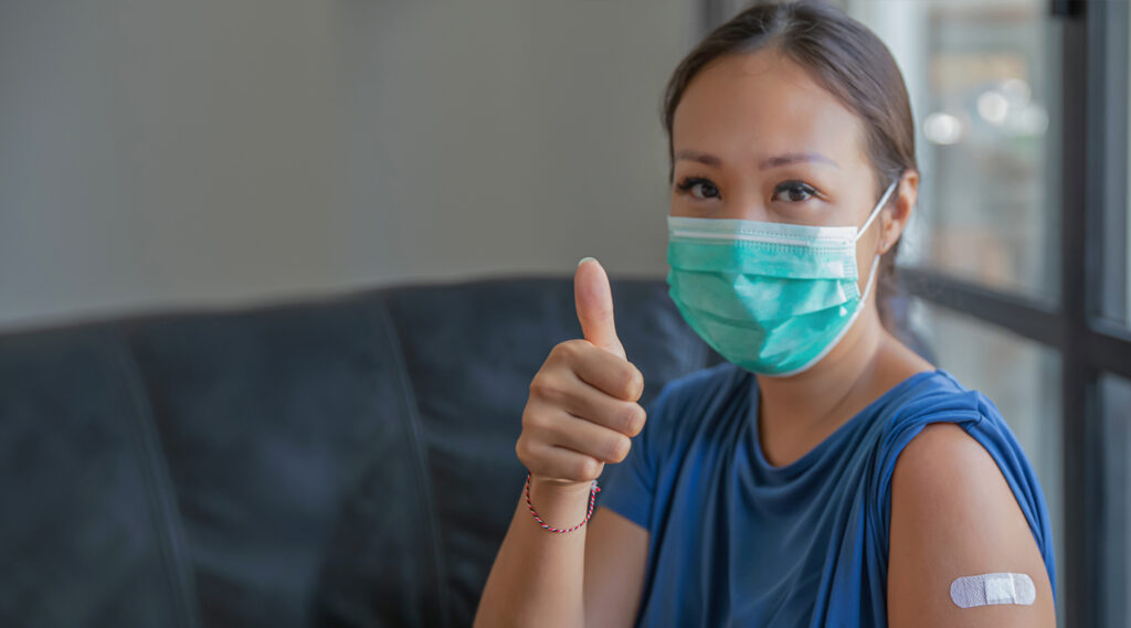 Female patient wearing mask gives a thumbs up