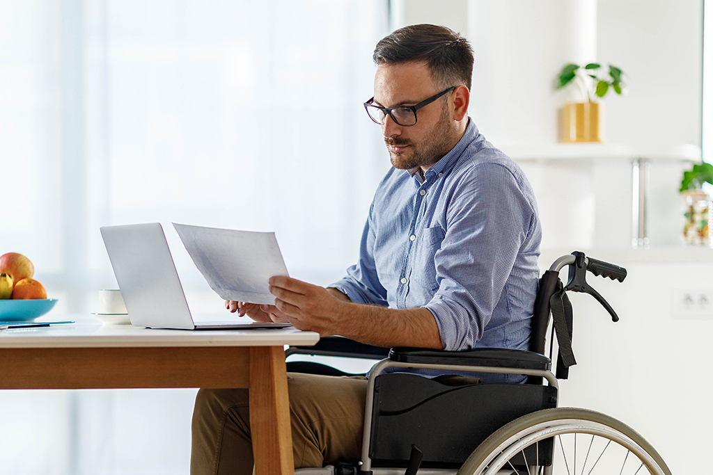 Disabled businessman reading reports while working at home.