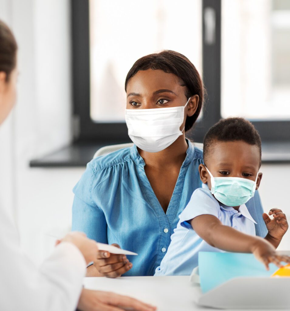 Mother with baby son in masks and doctor at clinic