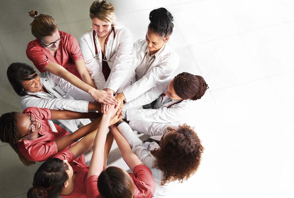 Circle of diverse female medical professionals put hands together