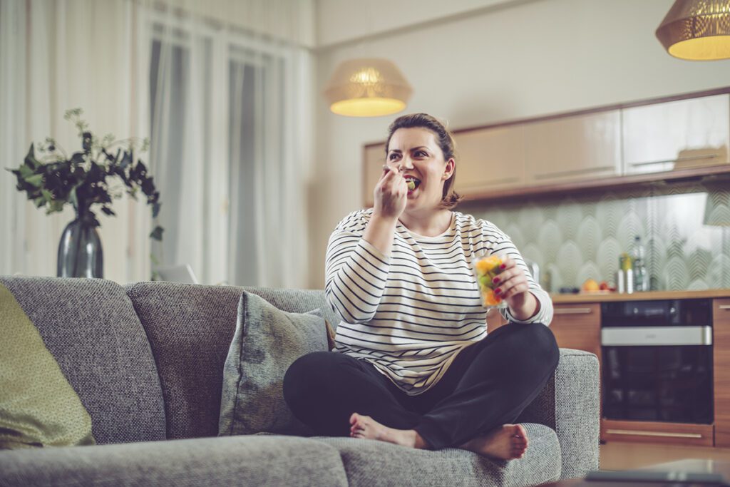 Woman eat fruit sitting on a sofa