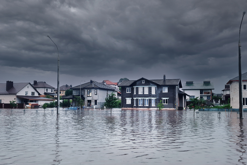 Flooded street in front of homes with a stormy sky