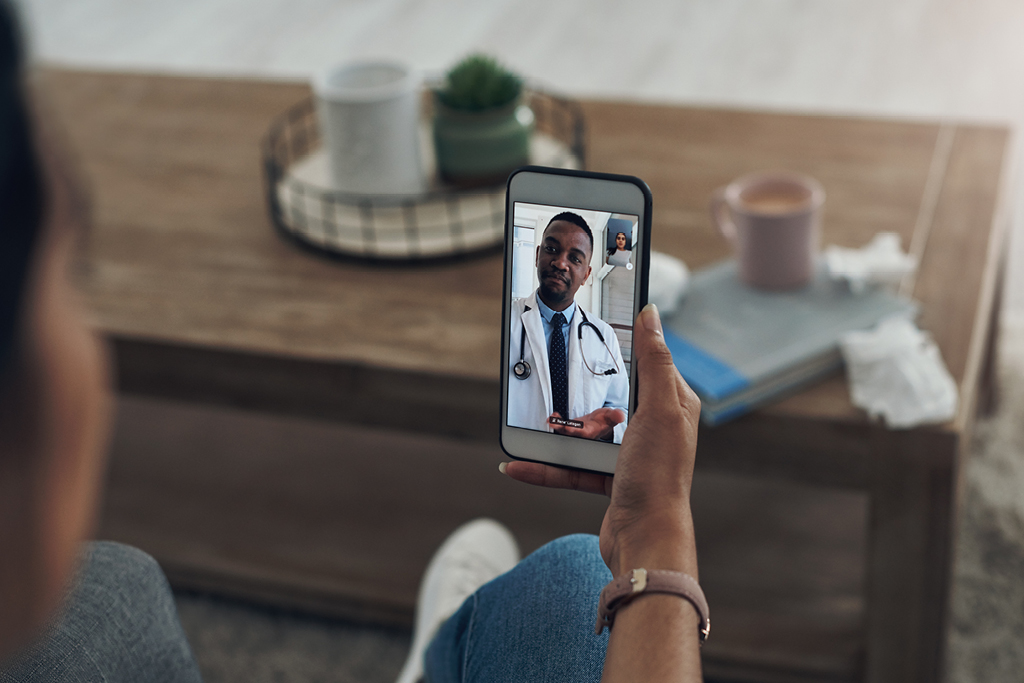 Person holding a cell phone with a provider for a telehealth video