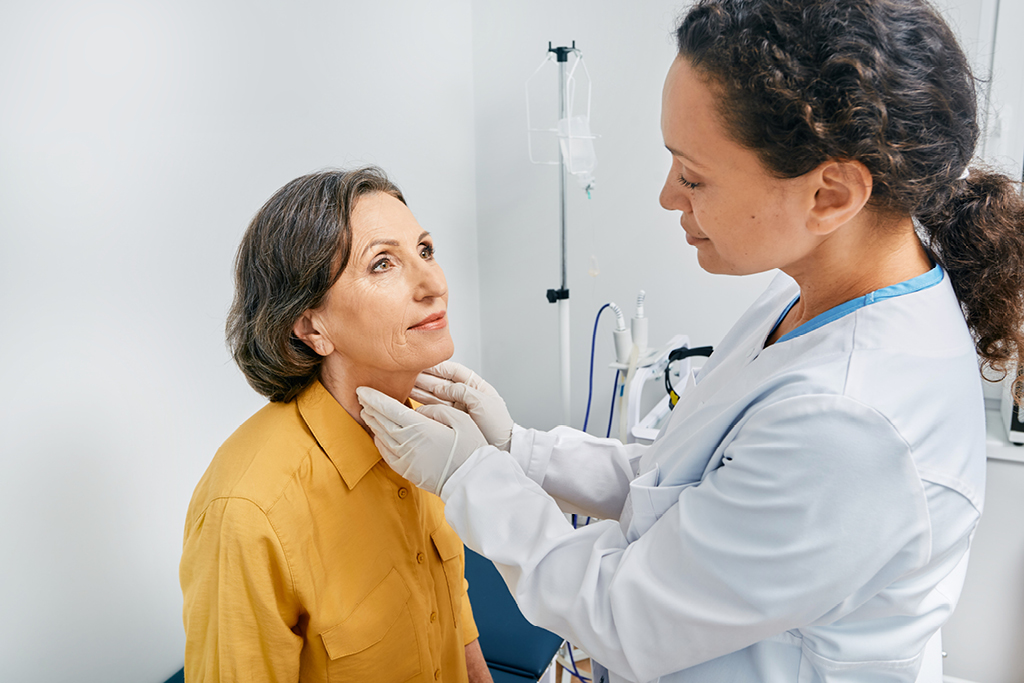 Doctor checking female patient's thyroid