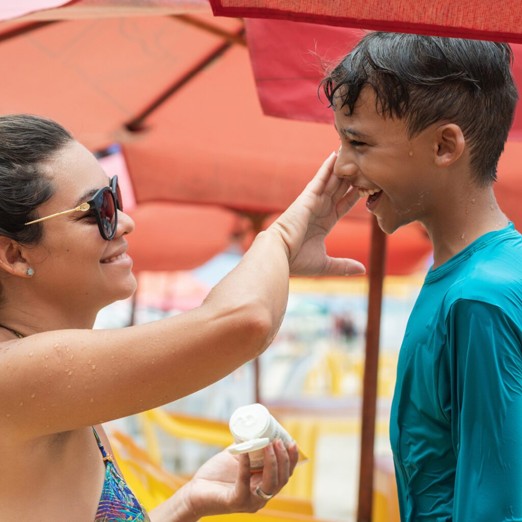 Woman applying sunscreen on boy