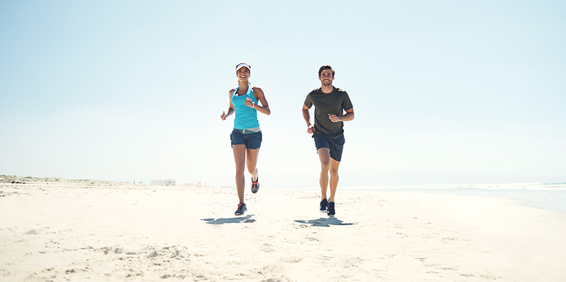 A man and a woman running on the beach